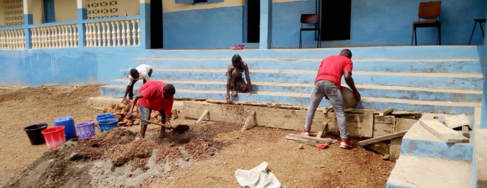 Mannen-repareren-de-afwatering-van-de-school-in-Heremakono
